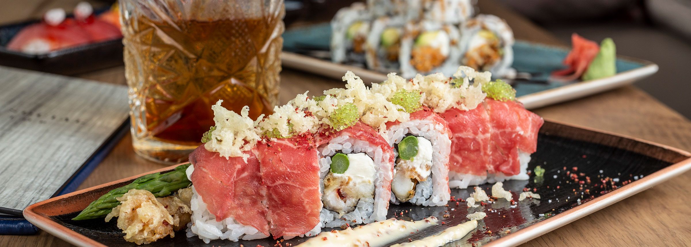 Plated sushi roll with bourbon cocktail