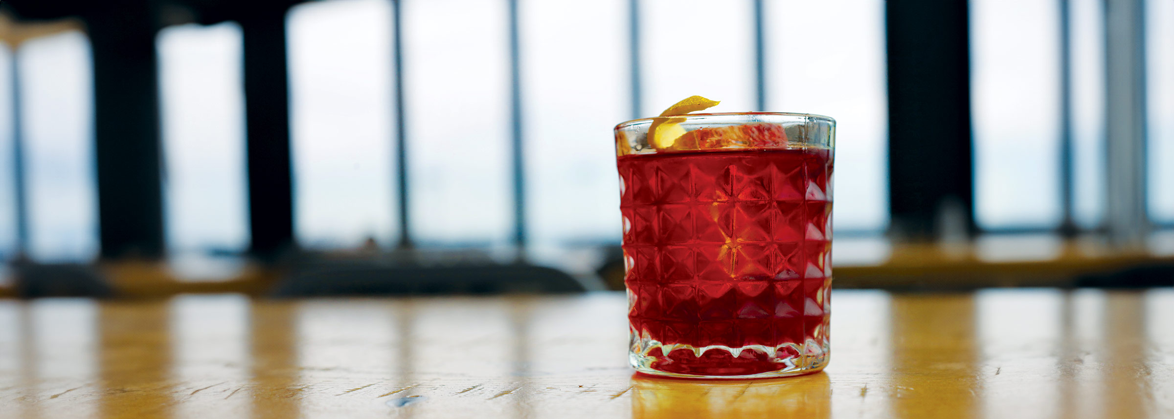 A close up of a manhattan cocktail on a bartop.